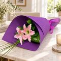 2 pretty wrapped lily stems presented as a bunch with paper and ribbon