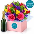 Bright mix of fresh blooms set in a box with a bottle of sparkling wine