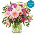 Pastel blooms of various flowers comes with glass vase
